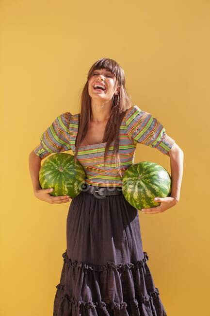 Laughing woman holding watermelons — Stock Photo