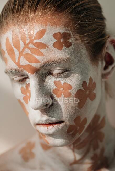 Retrato de jovem com rosto branco e arte corporal com flores — Fotografia de Stock