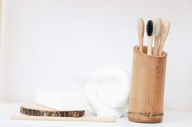 Bamboo toothbrushes in a container next to a bar of soap and a towel — Stock Photo