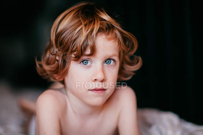 Porträt eines kleinen rothaarigen Jungen, der auf dem Bett liegt — Stockfoto