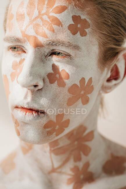 Retrato de hombre joven con cara blanca y arte corporal con flores - foto de stock