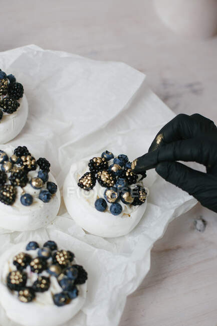 Frau dekoriert Pavlova-Desserts mit Blaubeeren und Brombeeren — Stockfoto