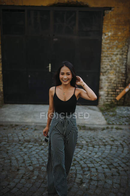 Стильна азіатська жінка, що йде на вулиці і посміхається — стокове фото