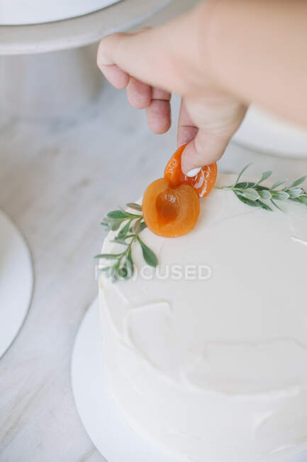 Жінка прикрашає торт з персиками і листям — стокове фото