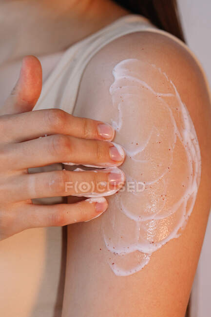 Femme frottant crème sur son bras — Photo de stock