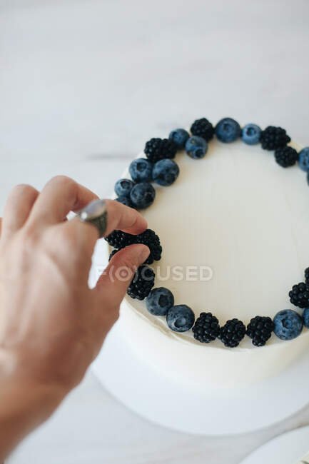 Frau dekoriert Kuchen mit Blaubeeren und Brombeeren — Stockfoto