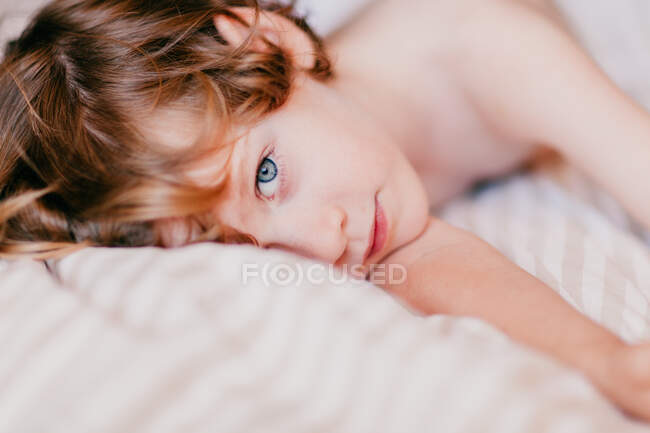 Портрет маленького рыжего мальчика, лежащего на кровати — стоковое фото