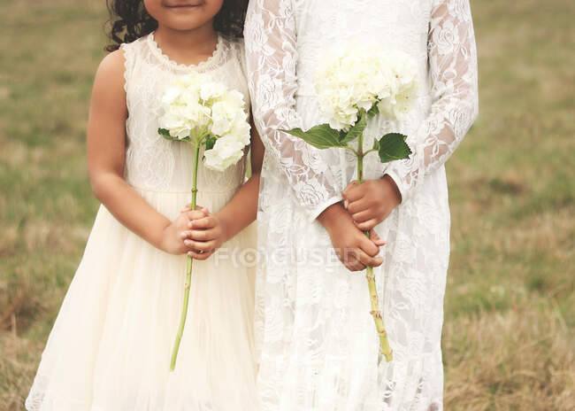 Two girls in vintage dresses holding hydrangea flowers, United States — Stock Photo