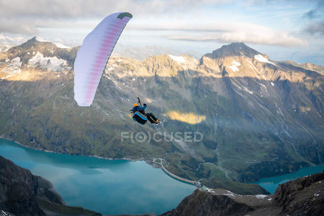 Man paragliding above alpine water reservoirs above Kaprun, Zell am See, Salzburg, Austria — Stock Photo
