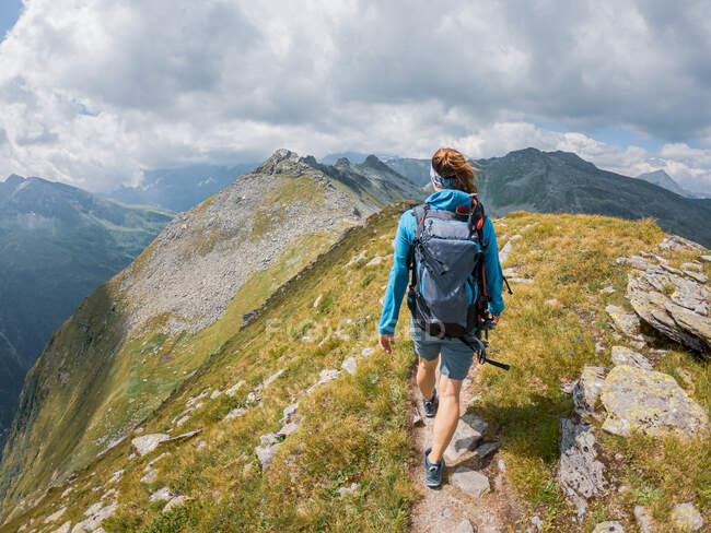 Mujer en ropa deportiva senderismo en hermoso paisaje montañoso - foto de stock