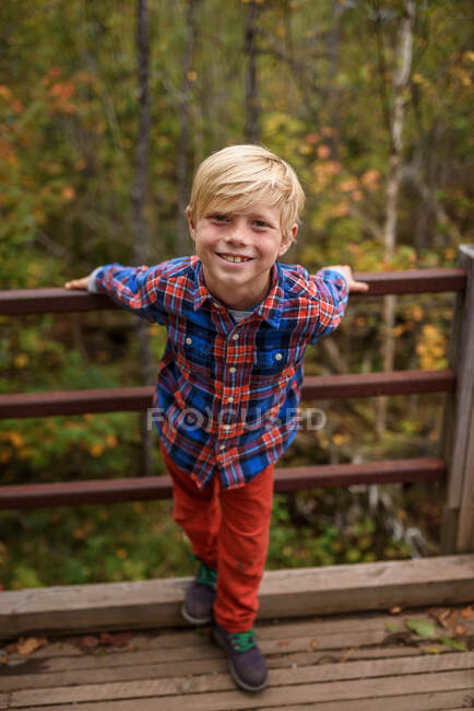 Retrato de un niño sonriente parado en un puente, Estados Unidos - foto de stock