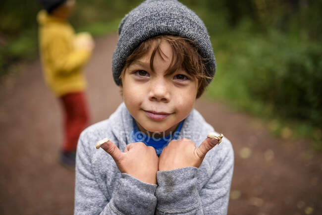 Portrait of a boy standing in the forest with mushrooms on his fingers, United States — Stock Photo