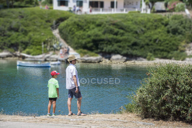 Pai e filho em pé à beira-mar, Menorca, Espanha — Fotografia de Stock