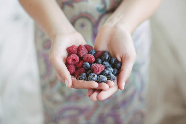 Woman holding a handful of blueberries and raspberries — Stock Photo