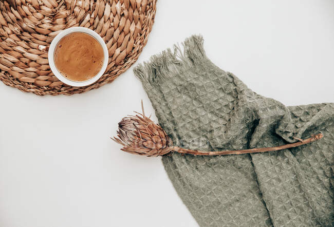 Xícara de café ao lado de uma flor de proteína seca e um cobertor — Fotografia de Stock