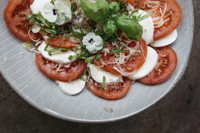 Mozzarella, tomato and basil salad with edible violets — Stock Photo