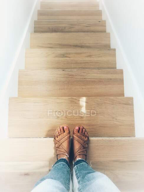 Mujer de pie en la parte superior de una escalera - foto de stock