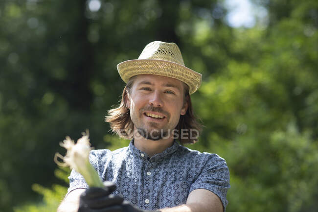 Porträt eines Mannes, der im Garten steht und eine Pflanze hält, Deutschland — Stockfoto