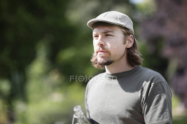Portrait of a man standing in garden holding a bottle of water, Germany — Stock Photo