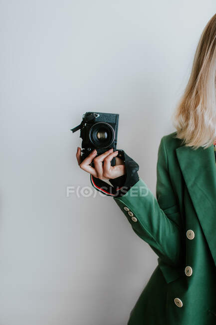 Жінка в зеленому піджаку тримає старовинну камеру — стокове фото