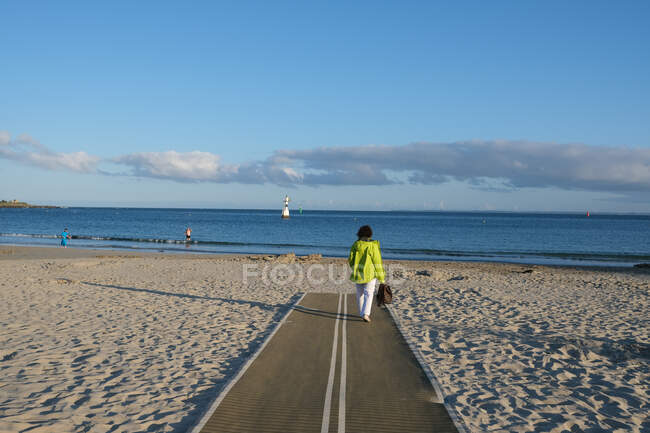 Mujer caminando en la playa de Quiberon, Bretaña, Francia - foto de stock