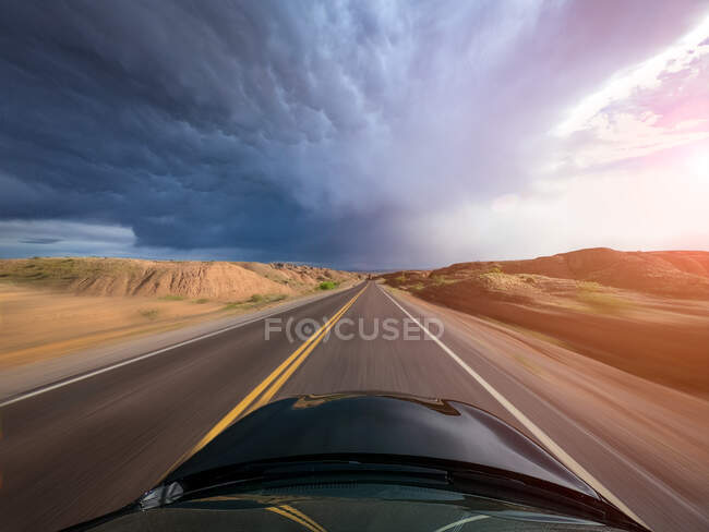 Car driving through a rural landscape towards a storm, United States — стоковое фото