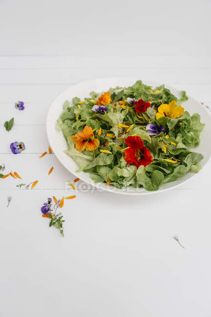 Teller mit grünem Salat mit essbaren Blumen — Stockfoto