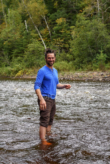 Hombre sonriente lavándose el pelo en un río, Estados Unidos - foto de stock