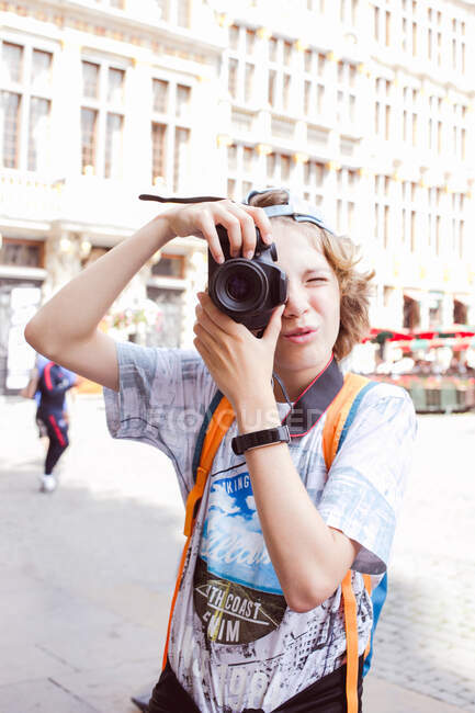 Niño de pie en Grand Place tomando una foto, Bruselas, Bélgica - foto de stock