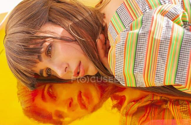 Portrait d'une femme couchée sur une feuille holographique — Photo de stock