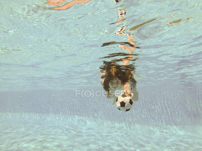 Menino nadando debaixo d 'água com uma bola — Fotografia de Stock
