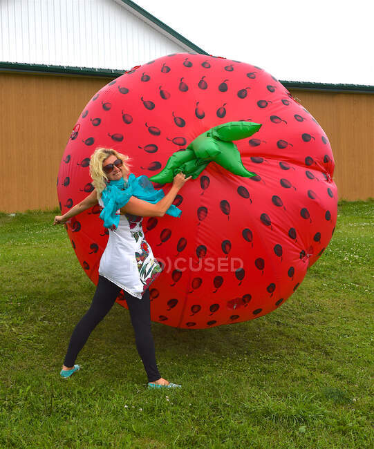 Smiling woman playing with a large inflatable strawberry balloon — Stock Photo