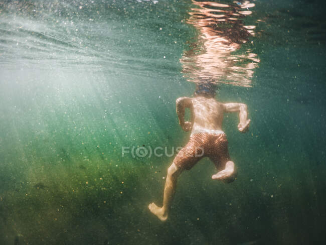 Unterwasserblick eines Jungen, der in einem See schwimmt, USA — Stockfoto
