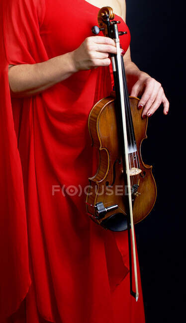 Женщина в красном платье держит скрипку — стоковое фото