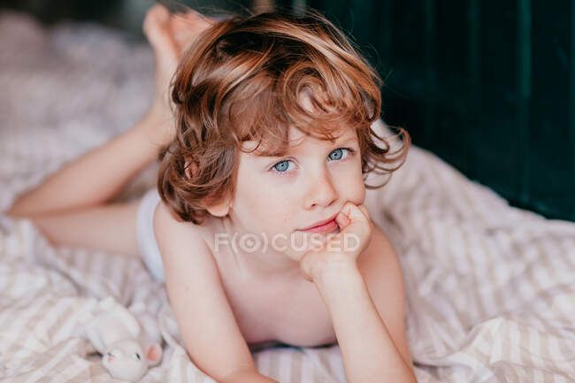 Portrait of little redhead boy lying on bed — Stock Photo