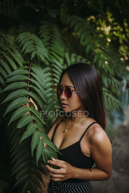 Asiatische junge Frau posiert mit grünen Baumblättern — Stockfoto