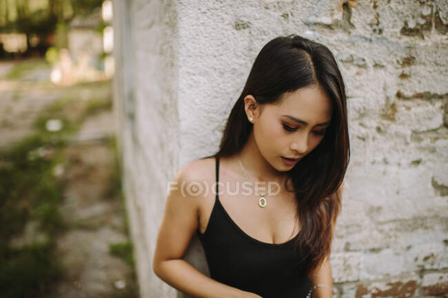 Portrait de jeune asiatique femme debout par mur — Photo de stock