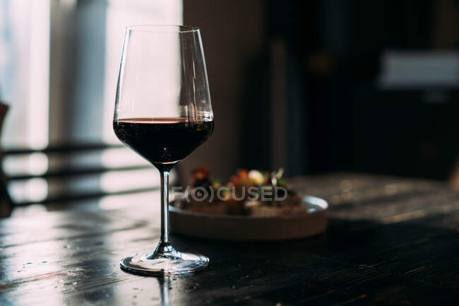 Glass with red wine on the wooden table in the bar — Stock Photo