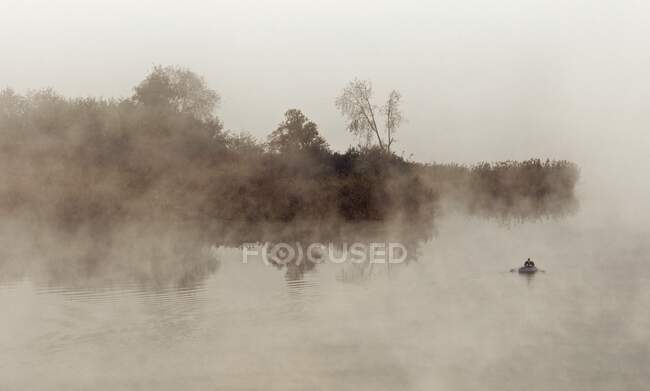 Людина, яка веслує на озері Дідзіуліс у ранковому тумані Тракай (Литва). — стокове фото