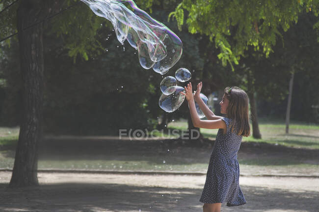Menina brincando com bolhas gigantes em um parque, França — Fotografia de Stock