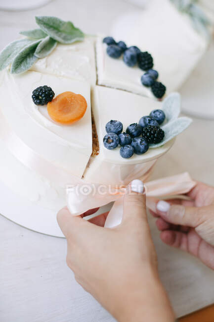 Frau bindet vier Scheiben Kuchen zu einem zusammengesetzten Kuchen zusammen — Stockfoto