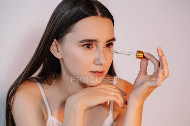 Mulher aplicando soro no rosto — Fotografia de Stock