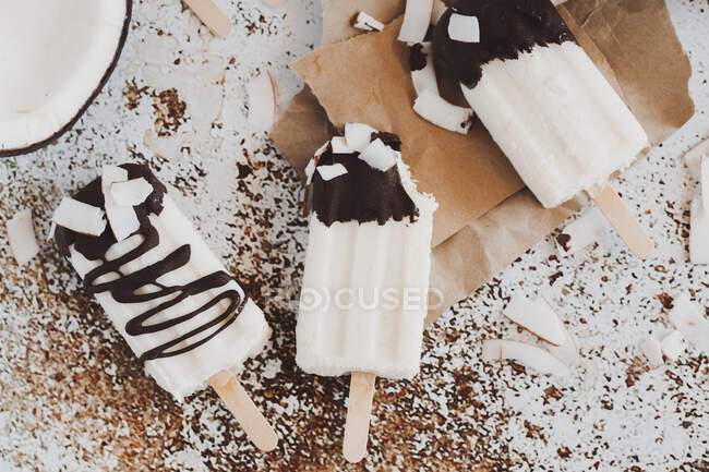 Três iogurte de coco e picolés de chocolate em uma mesa — Fotografia de Stock