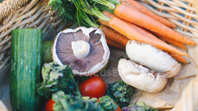 Zanahorias frescas, champiñones, pepino y tomates en cesta - foto de stock