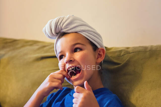 Menina sentada em um sofá usando fio dental nos dentes após o banho — Fotografia de Stock