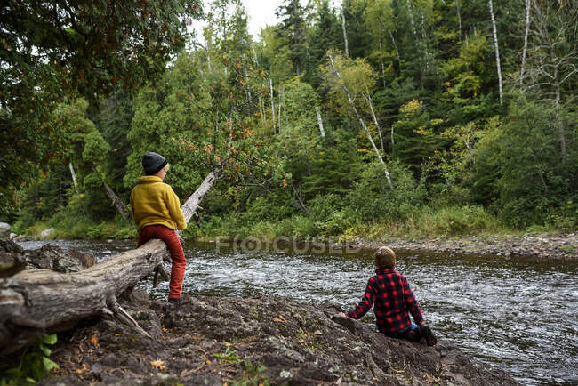 Dos chicos jugando al lado de un río, Estados Unidos - foto de stock