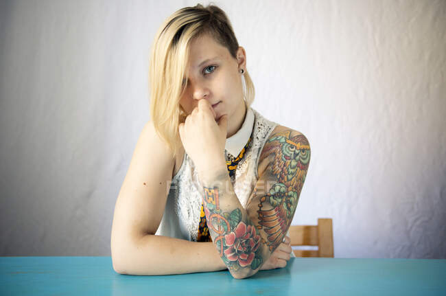 Портрет женщины с татуировкой на рукаве, сидящей за столом — стоковое фото