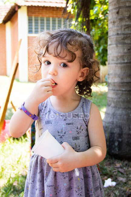 Chica de pie en el parque comiendo palomitas de maíz - foto de stock