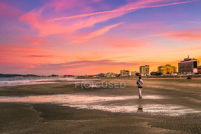 Femme marchant sur la plage au coucher du soleil, Riccione, Rimini, Italie — Photo de stock