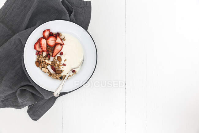 Yogur y granola con fresas frescas, granada y almendras - foto de stock